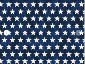 Close-up of blue fabric with white stars in a repeated pattern; inch ruler visible at the bottom as a fabric swatch.